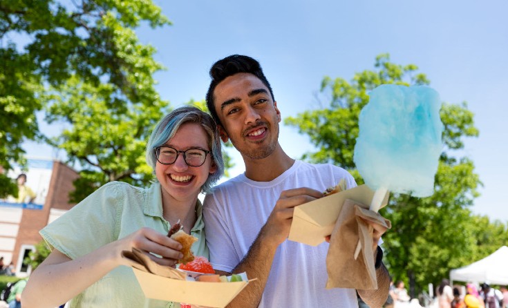 Two people smile while holding food in their hands