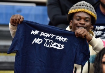 Person holds shirt that says &quot;We don&#039;t take no mess&quot;.