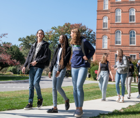 Students walk outside on campus while talking.