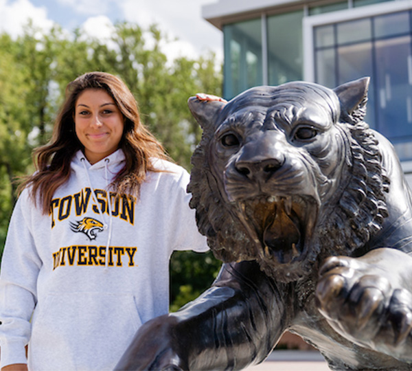 Person poses with a tiger statue at Towson university.