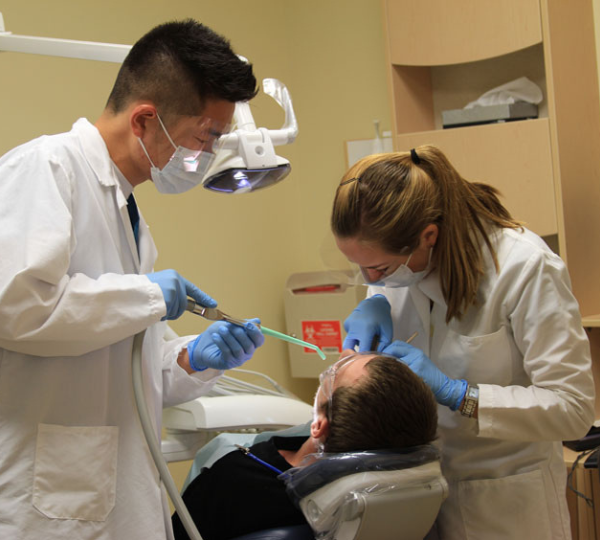 Two dentists working on a patient laying in a dentist chair.