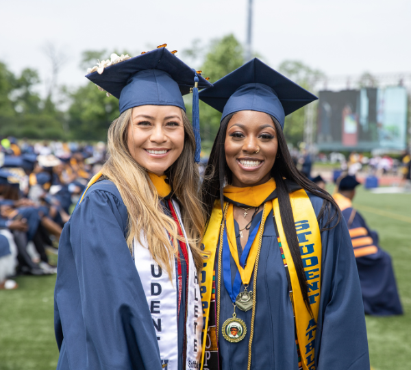 Two people pose for photos on graduation day in caps and gowns.