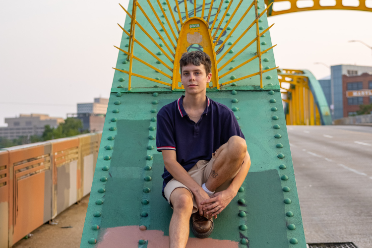 Portrait of person sitting on structure beam of bridge in Baltimore.