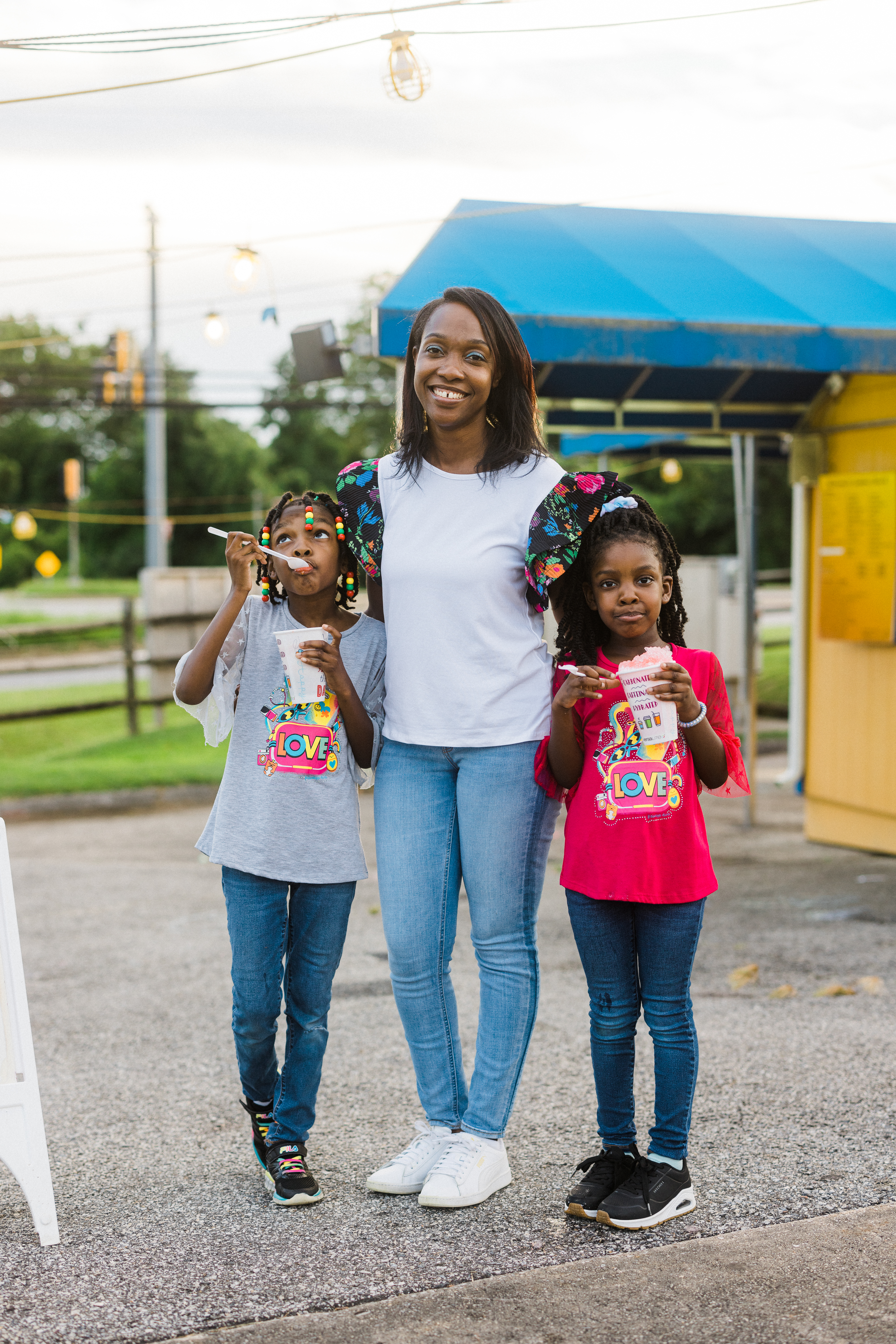 Mother and two children standing outside. The kids are eating snowballs.