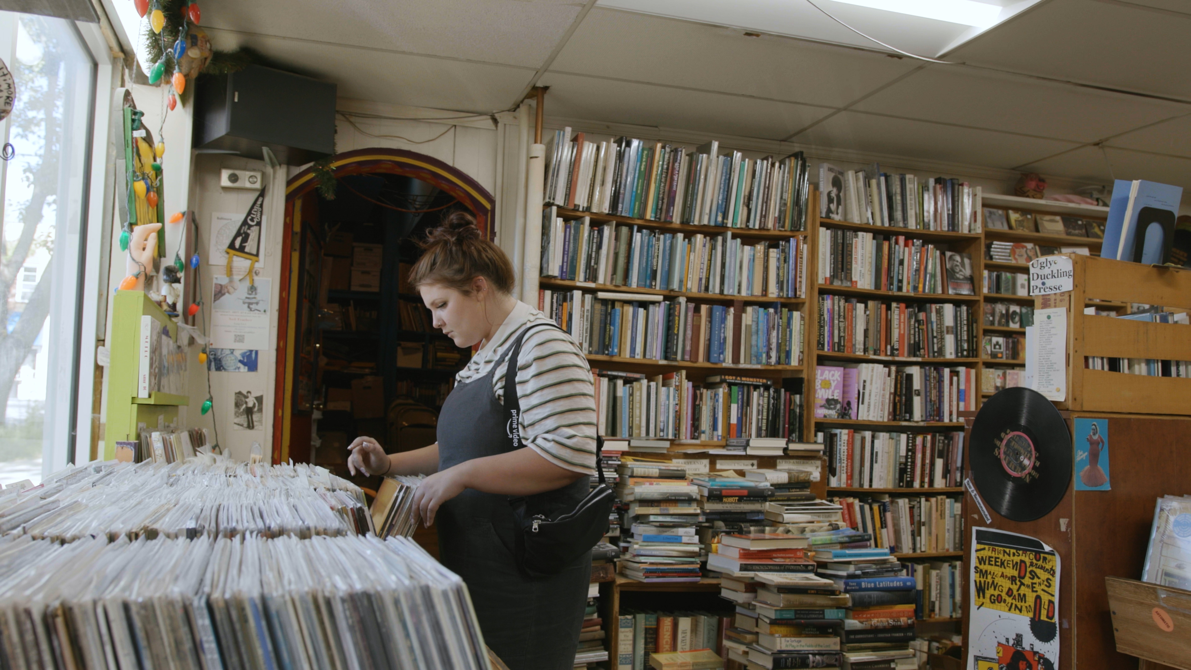 Person stands and looks through bin of records in a record store.