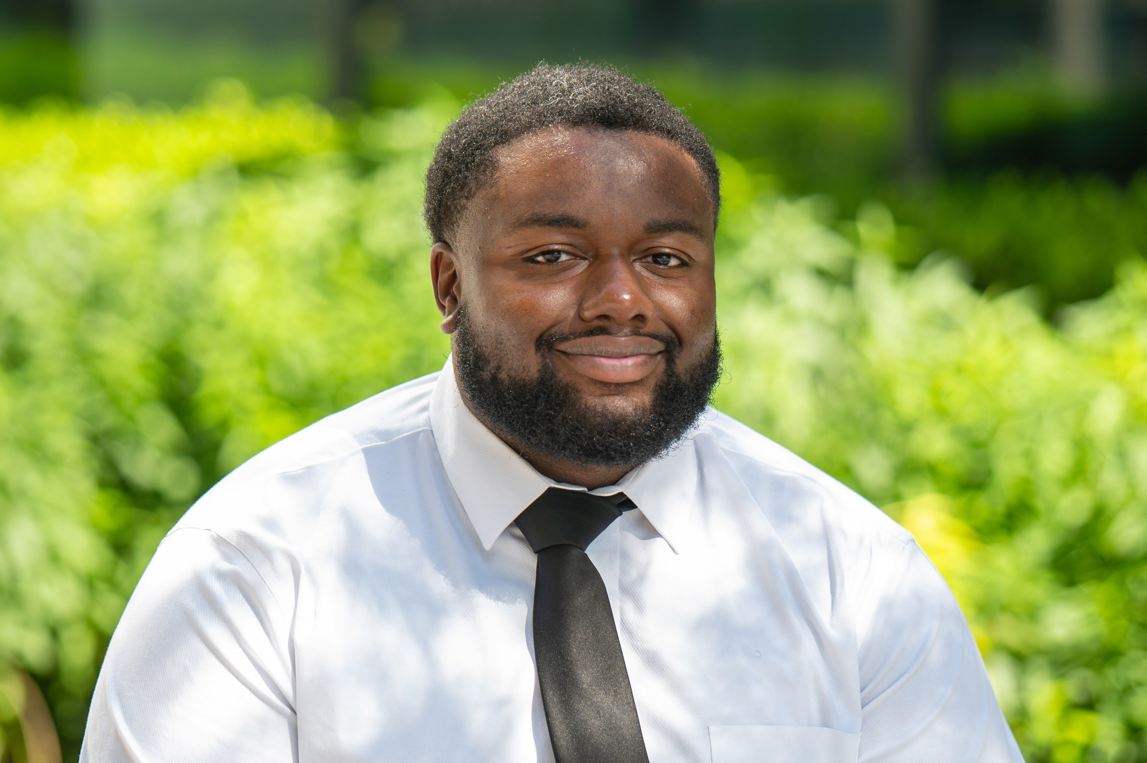 man who is black and young and wearing a tie and shirt against a green background