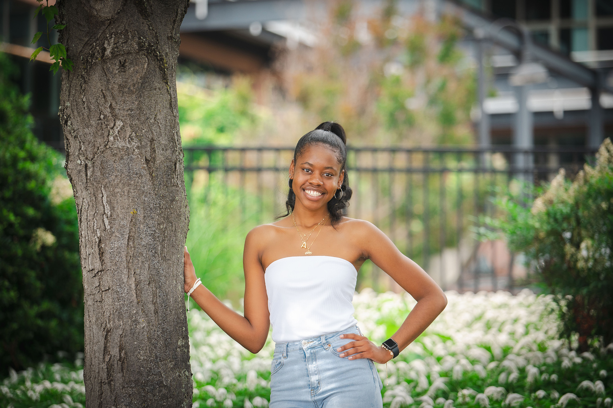 A student leaning against a tree and smiling in a Baltimore waterfront park