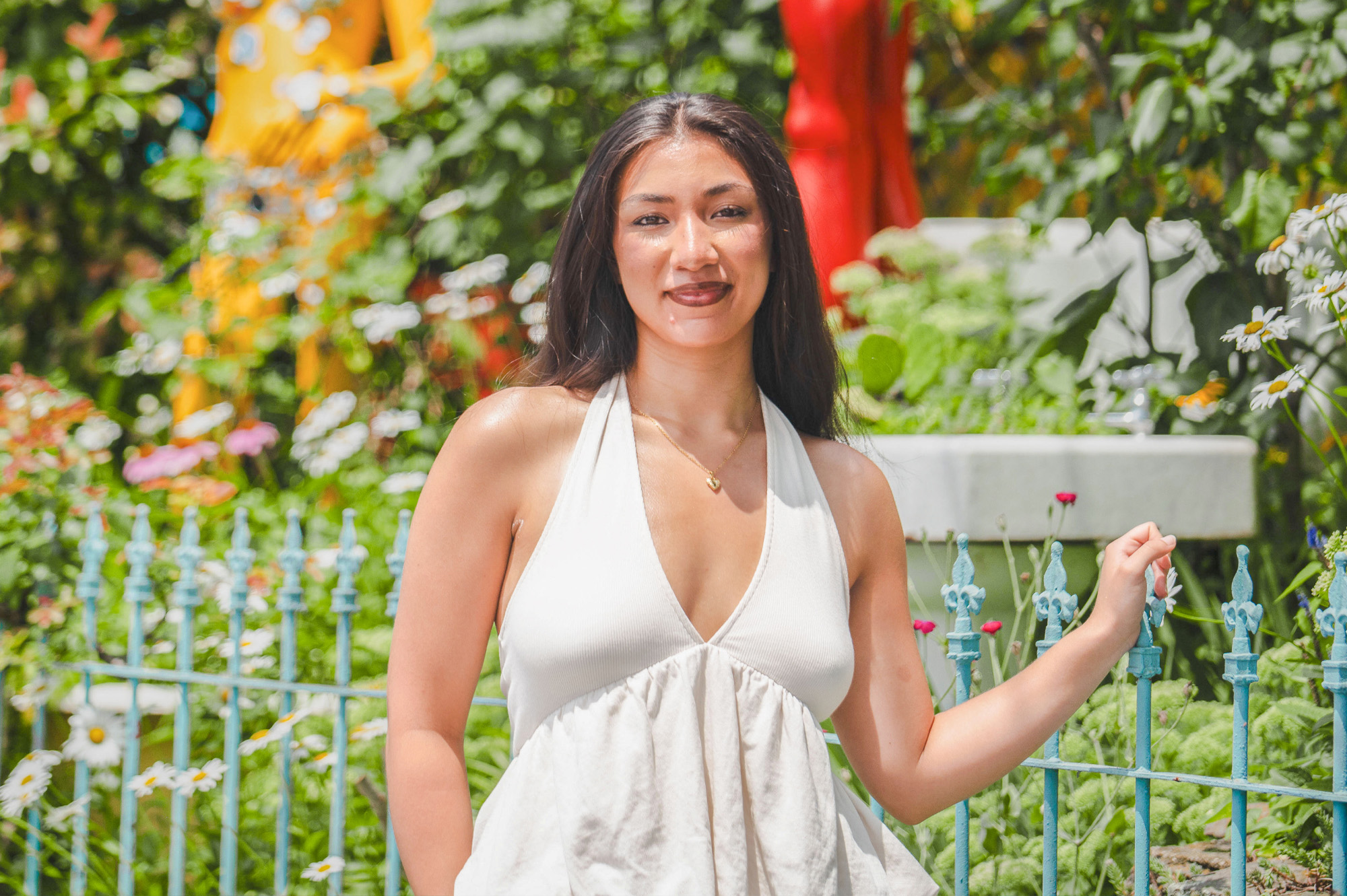 A student posing for a photo in front of a gated garden.