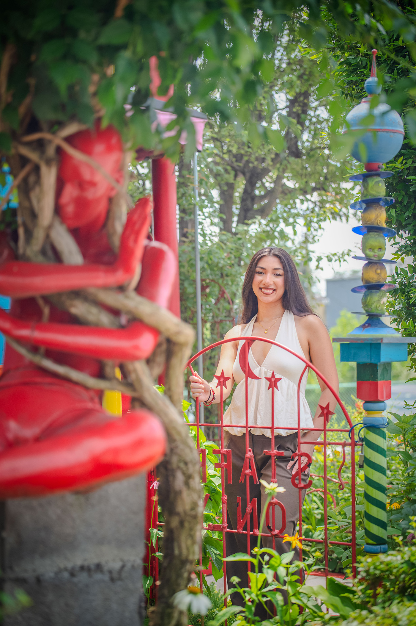 A student poses for a photo outside beside a red sculpture.