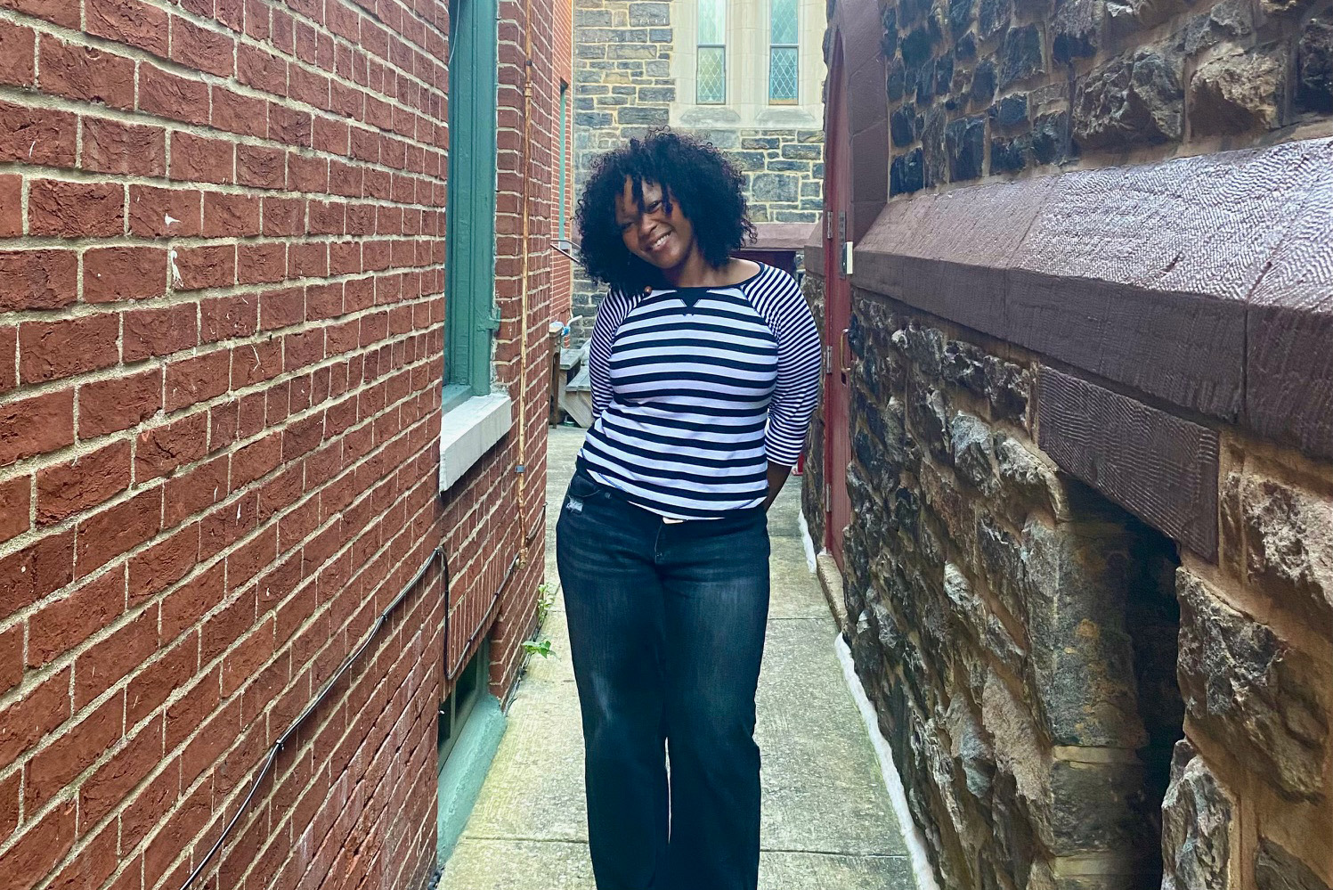 A student posing for a photo between two Baltimore buildings.