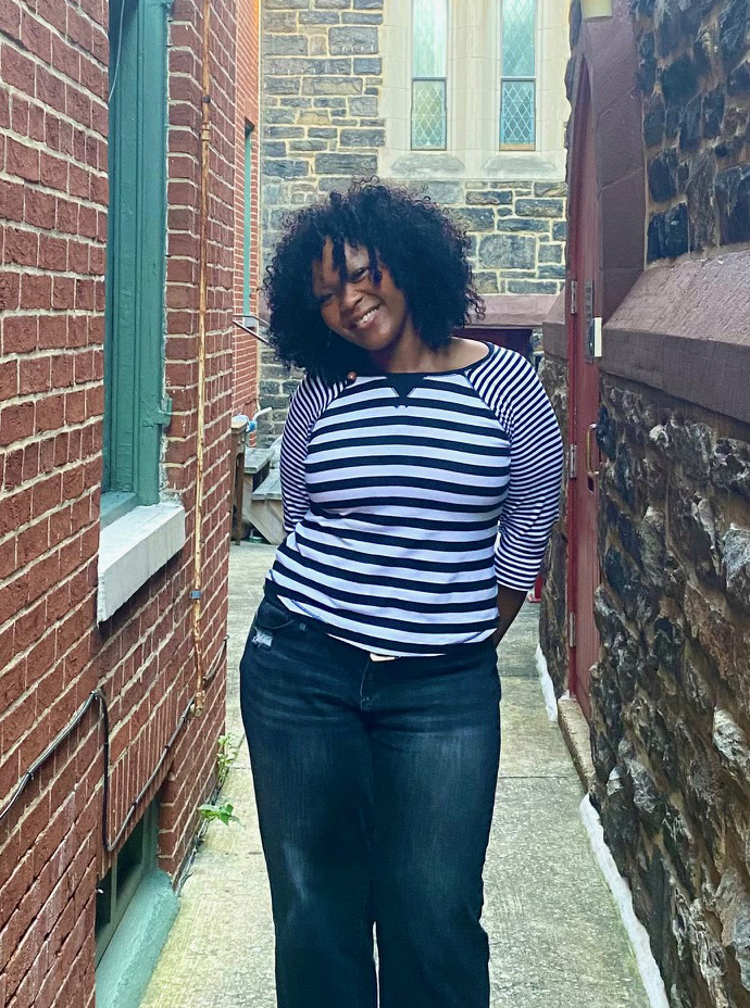 A student posing for a photo between two Baltimore buildings.