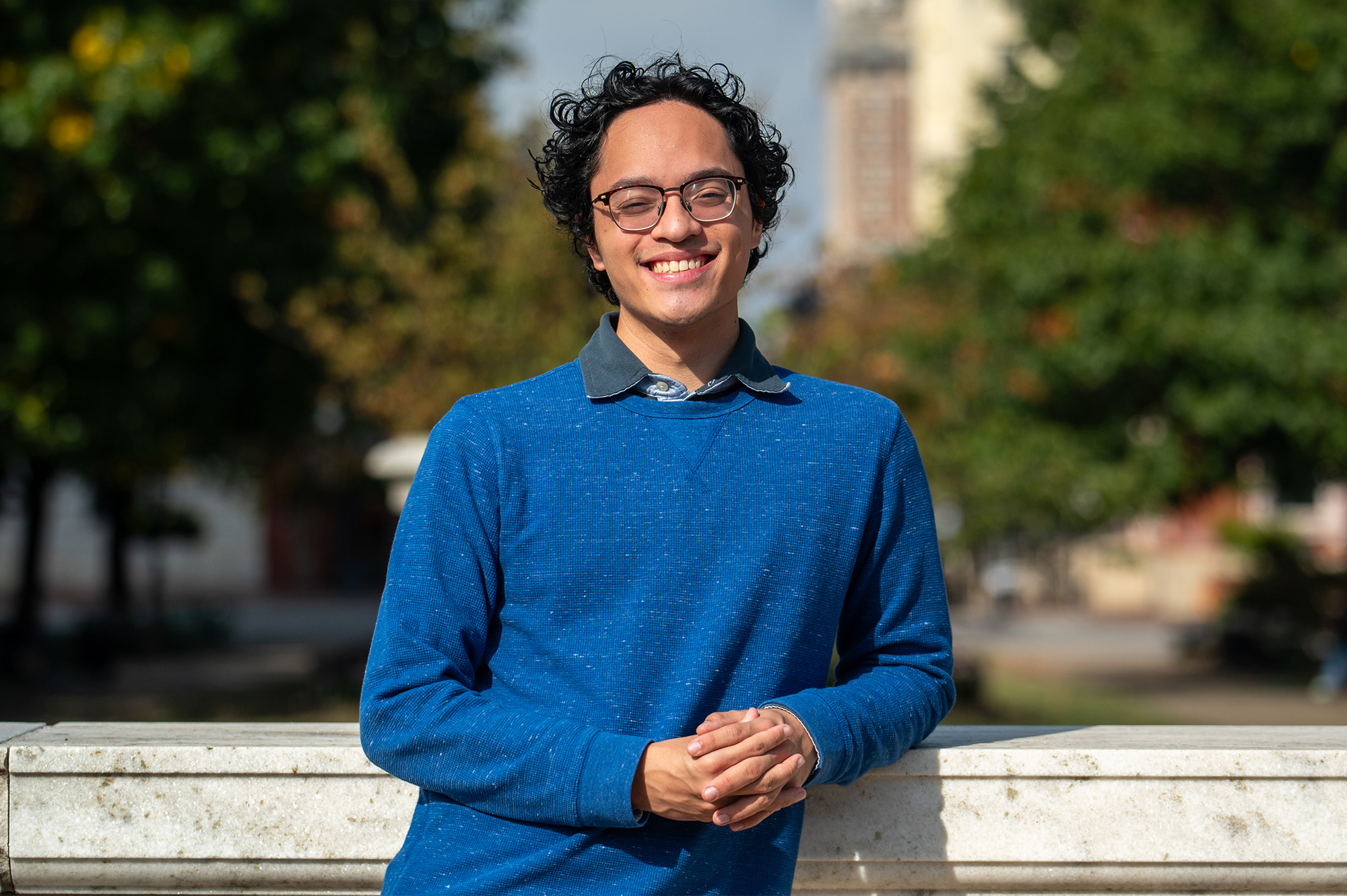 A student smiling in front of a park.
