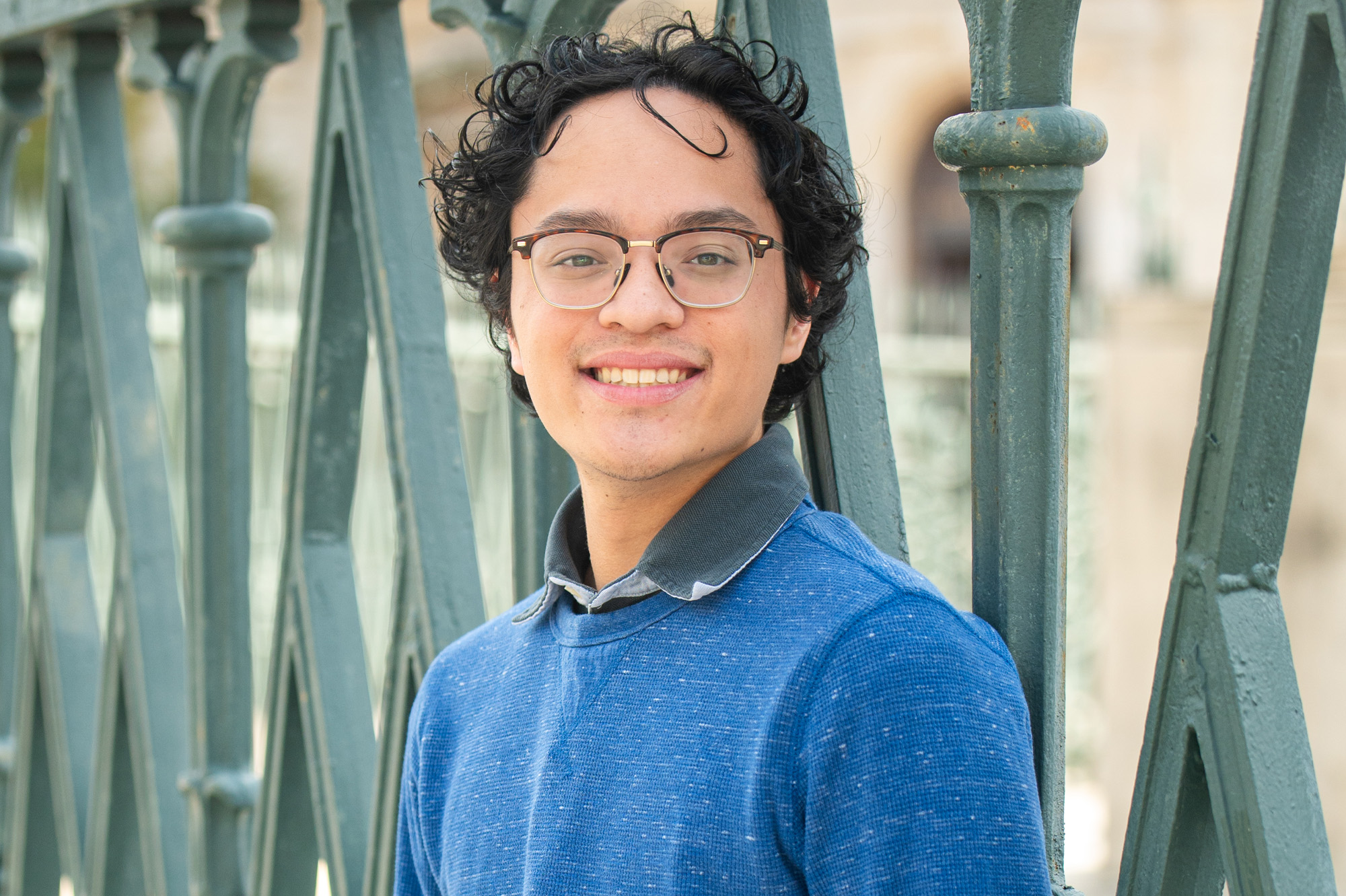 A student posing in front of an intricate gate near Peabody's campus in Baltimore.